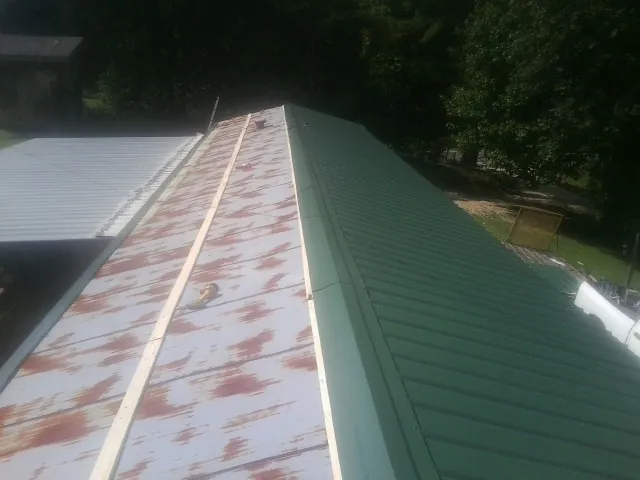 Old rusted panels beside newly installed green metal roofing — Wind Damage Roof Repair by Roofing Brothers in Fort Smith