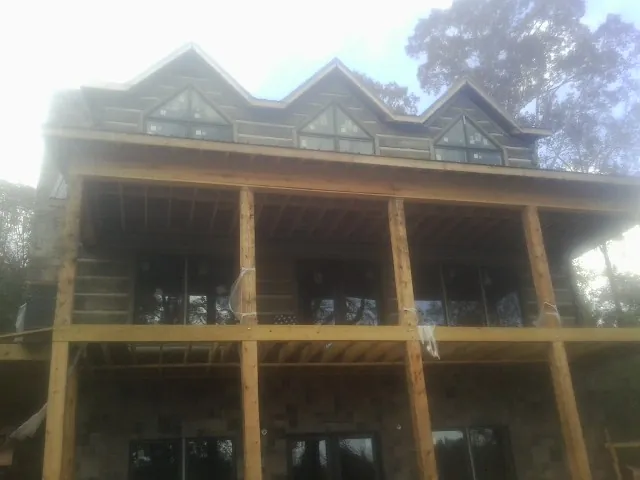Dormers and porch framing on a large log home under construction — Roof Coating work by our crew in Fort Smith