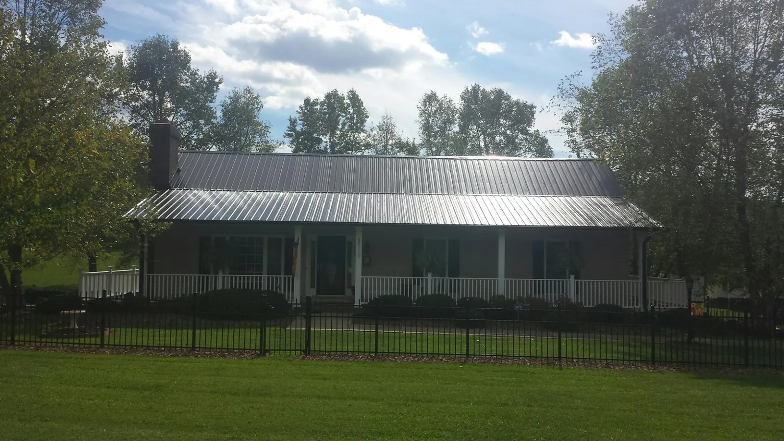 Gray metal roof on a brick ranch with a full width front porch — Gutter Guard Installation work by our crew in Fort Smith
