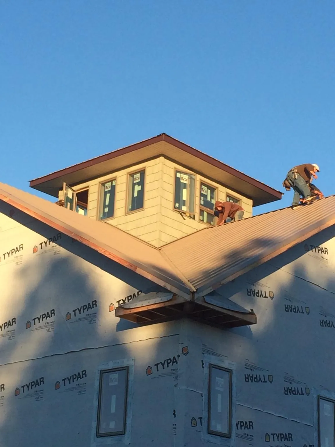 Roofers working around a rooftop cupola on a new metal roof at sunset — Roof Waterproofing in Fort Smith by Roofing Brothers